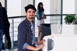 A young student smiling while playing a grand piano during a lesson.