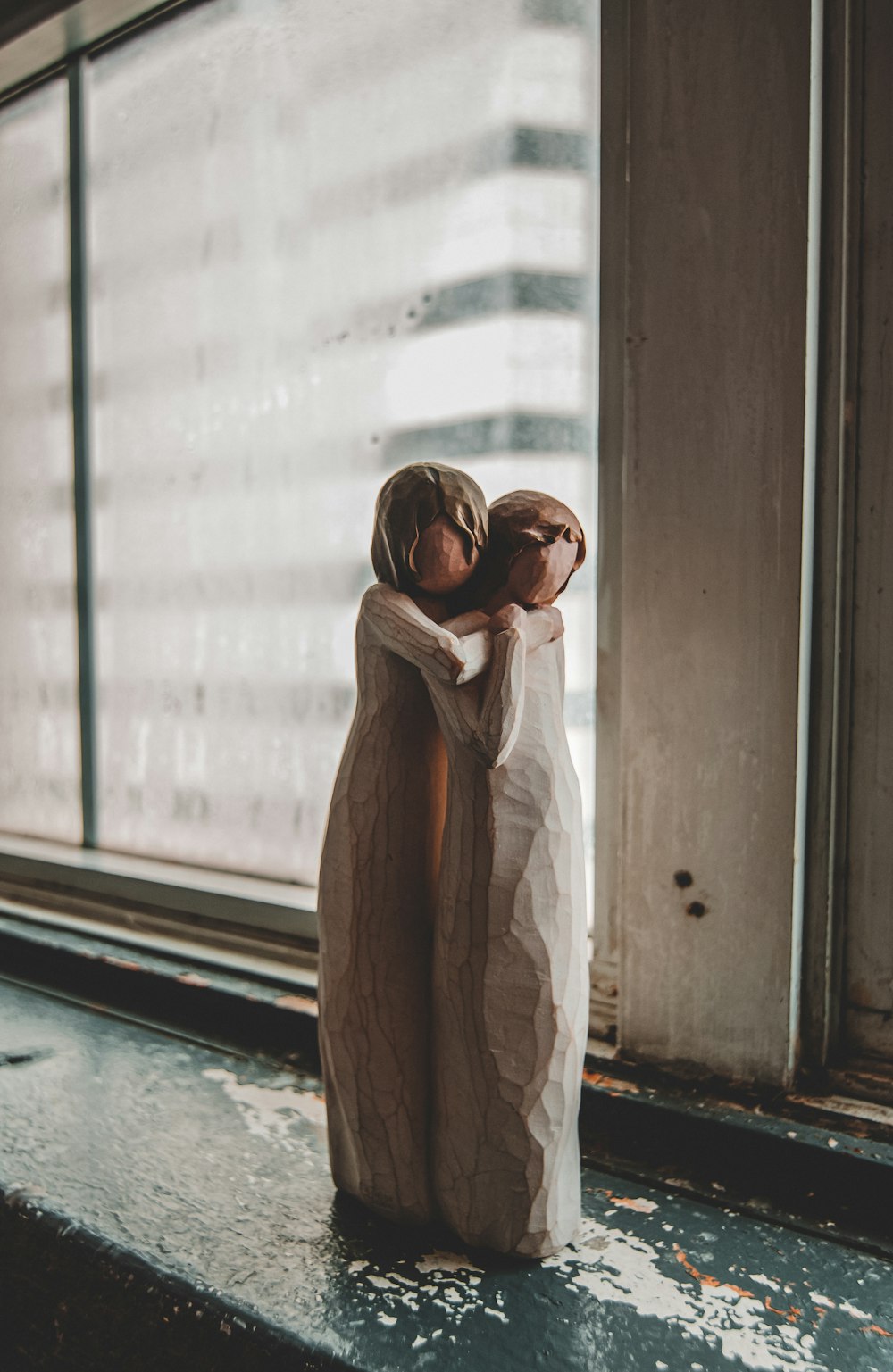 Willow Tree man hugging woman figurine near window