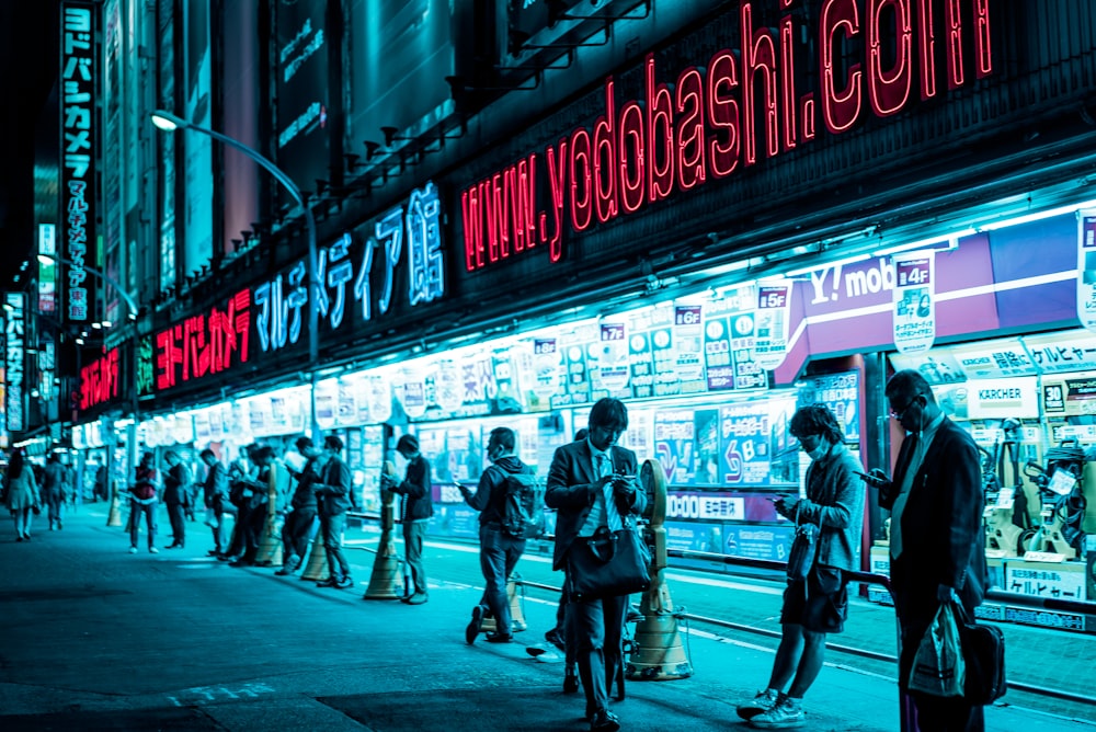 people standing near lighted building at night