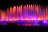 A vibrant nighttime fountain show with colorful water jets synchronized to music under blue lighting