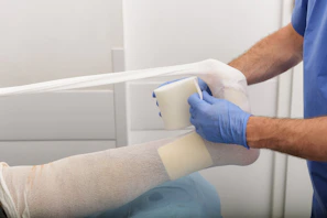 man putting medical bandage on left foot of person
