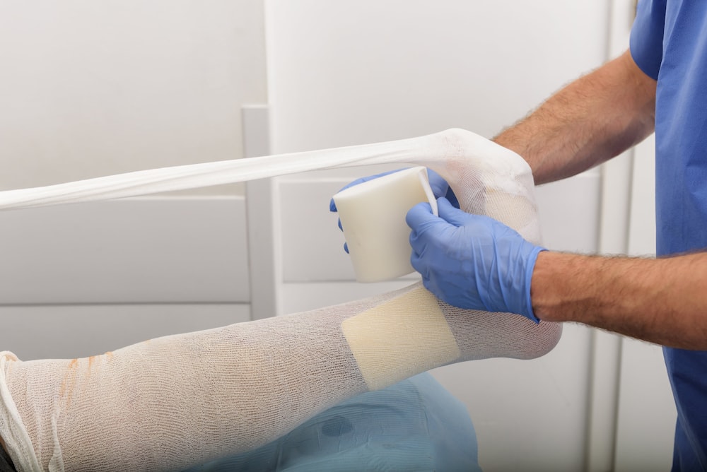 man putting medical bandage on left foot of person