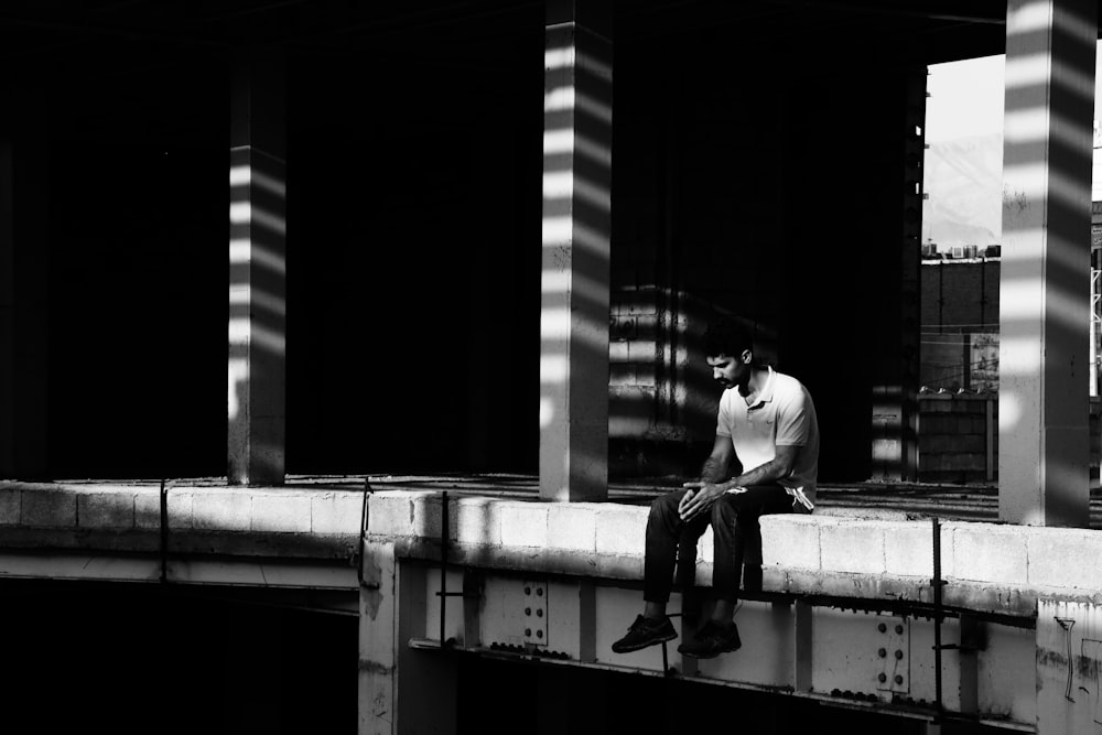 man sitting on concrete pavement looking down