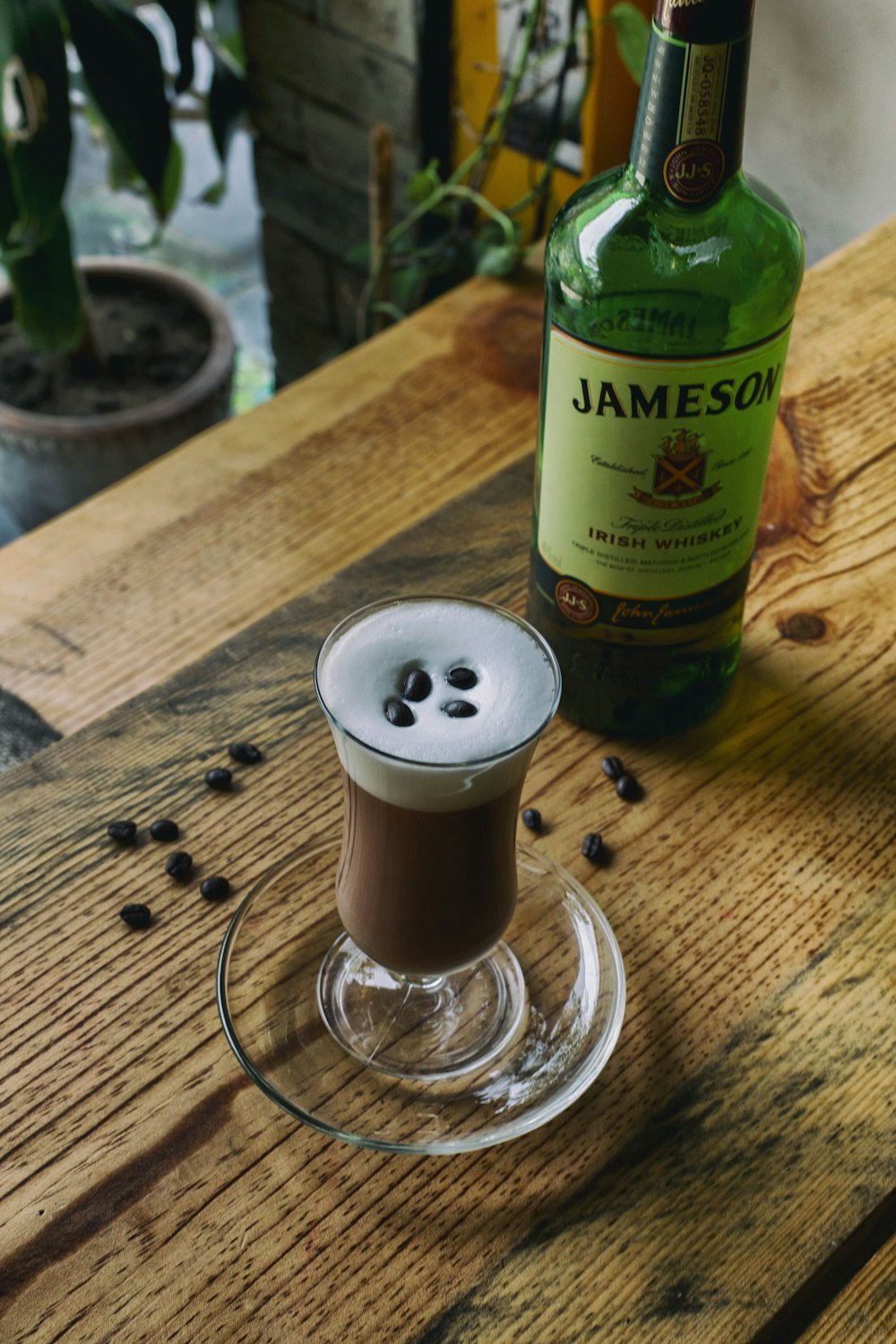 filled wine glass and Jameson bottle on brown table