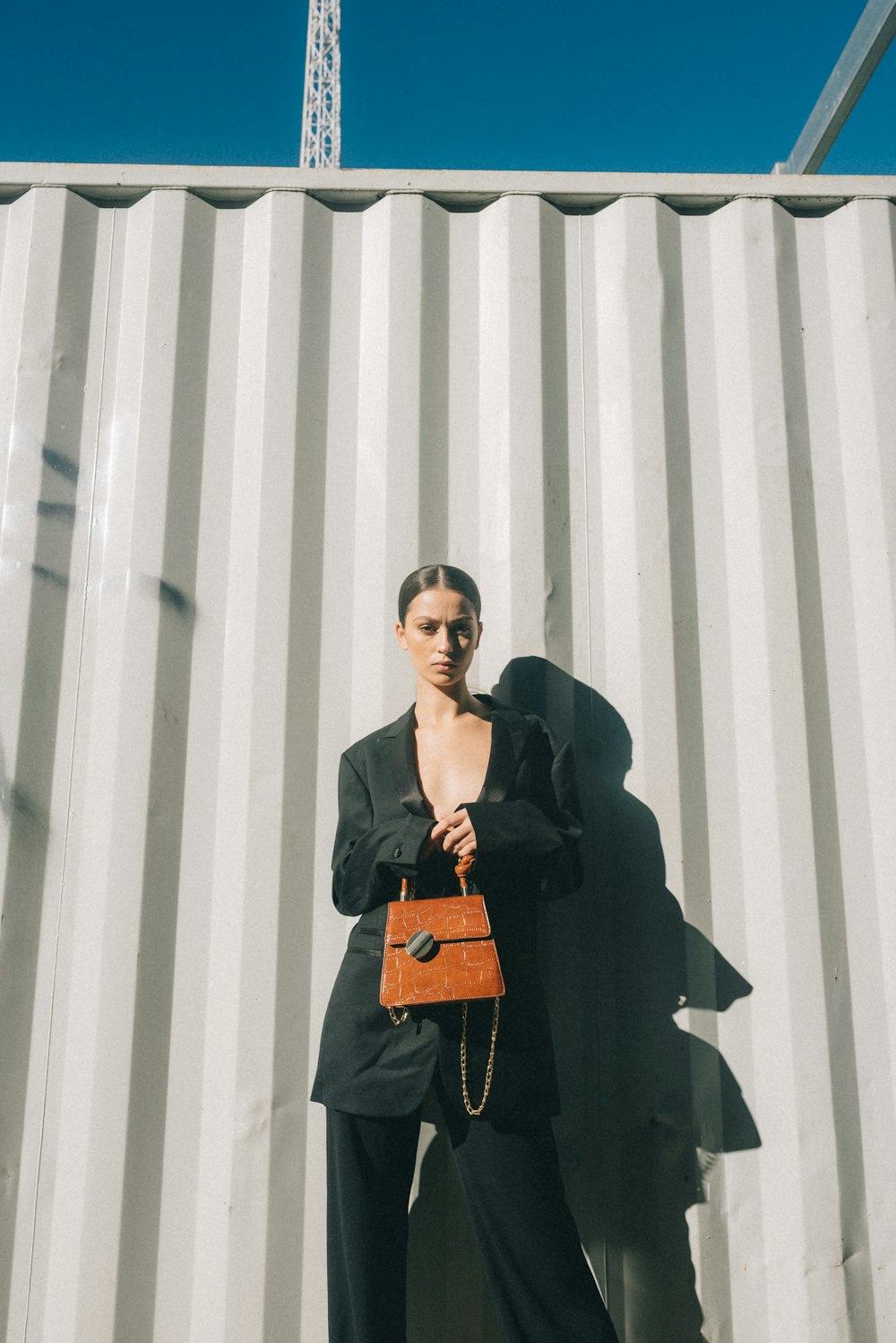 woman carrying leather handbag while standing near wall