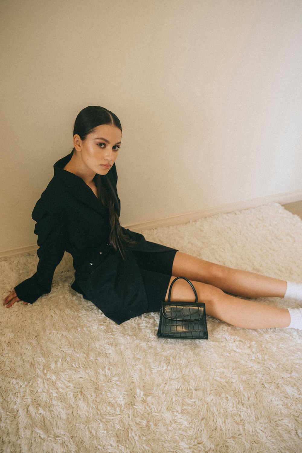 woman in black long-sleeved dress sitting on gray area rug