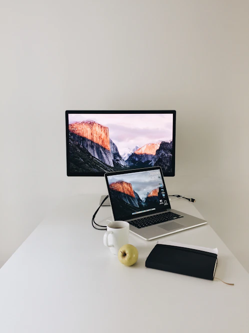 Minimalist workspace with a laptop, notebook, and coffee cup on a clean white desk