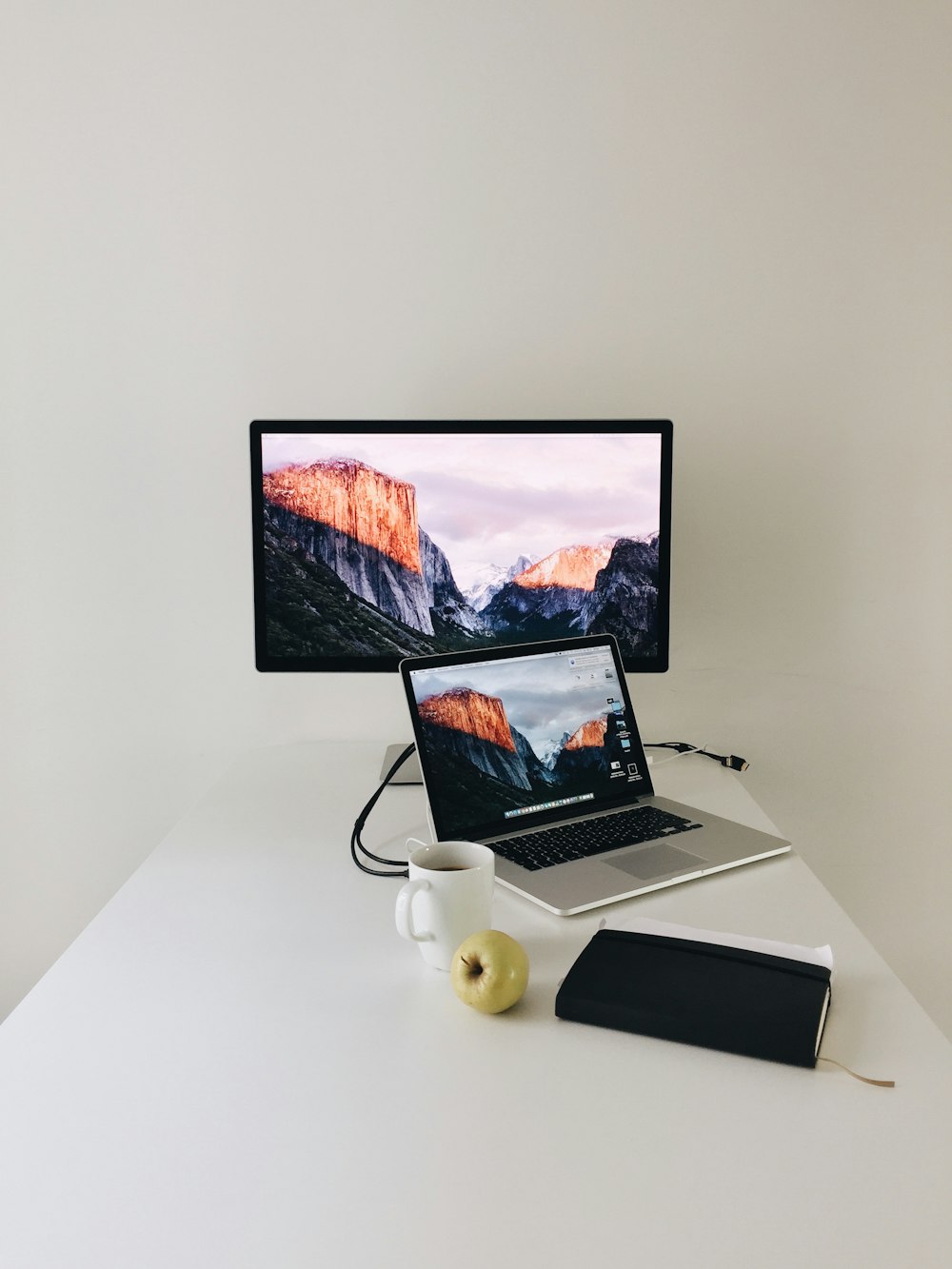 MacBook Pro in der Nähe des Apple Thunderbolt Displays auf dem Tisch