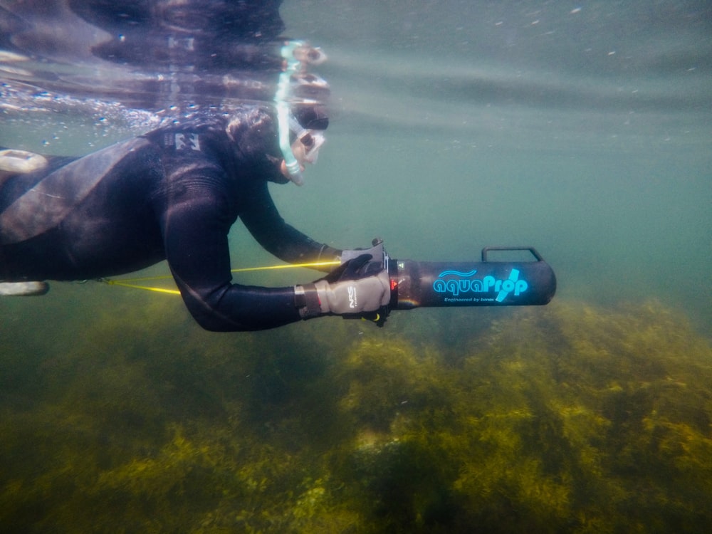 homem nadando no corpo de água segurando Aqua Prop máquina