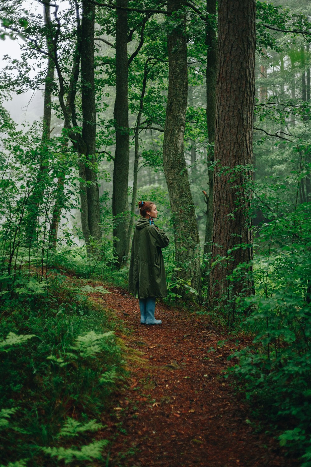 woman in black coat in front of trees