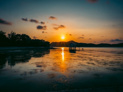A serene view of a floating house on tranquil waters at sunset.