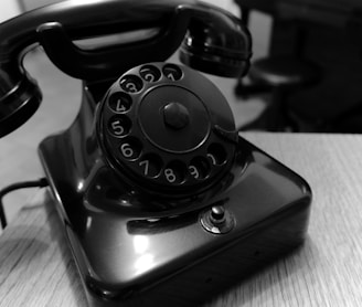 shallow focus photo of black rotary telephone