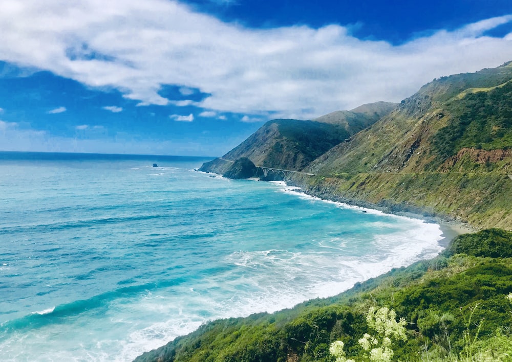 body of water crash on shore with mountains