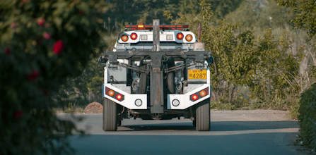 Taj Towing Company’s tow truck speeding down a road with emergency lights flashing.