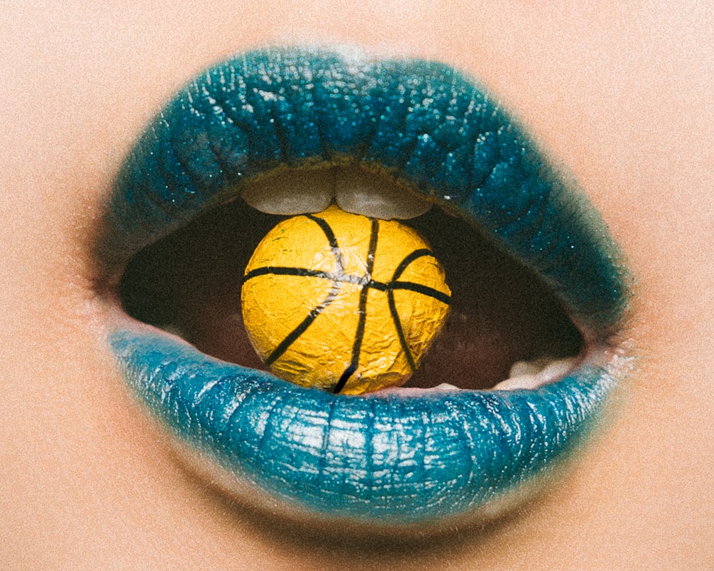 Persona che indossa il rossetto blu in procinto di mangiare caramelle da basket