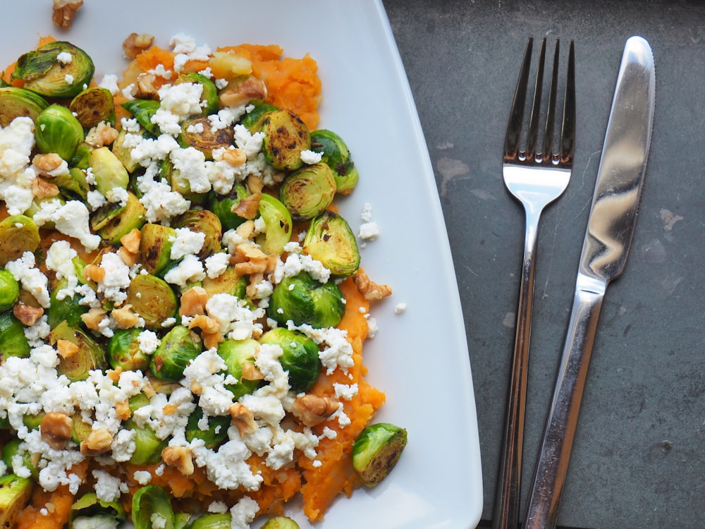 couteau de table et fourchette en acier inoxydable à côté des légumes cuits