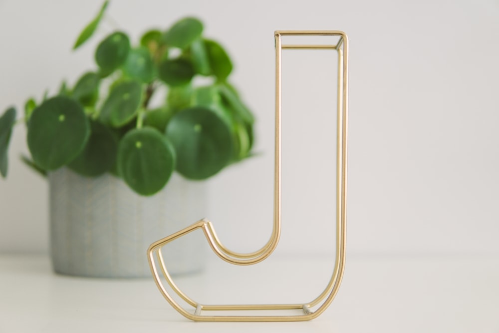 brass-colored decorative marquee letter J on table