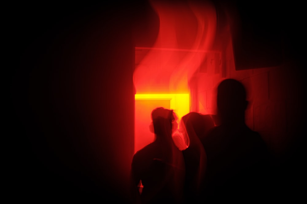silueta de personas dentro de la habitación iluminada en rojo