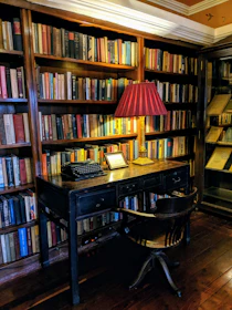 A classic mahogany desk with leather-bound ledgers and a vintage brass lamp.