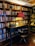 A vintage wooden desk set against a large bookshelf filled with an array of books. The desk is equipped with a classic typewriter and a framed picture. A small wooden chair is positioned in front of the desk. On the desk, a red-shaded lamp casts a warm glow, creating a cozy and inviting ambience.