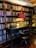 A vintage wooden desk set against a large bookshelf filled with an array of books. The desk is equipped with a classic typewriter and a framed picture. A small wooden chair is positioned in front of the desk. On the desk, a red-shaded lamp casts a warm glow, creating a cozy and inviting ambience.