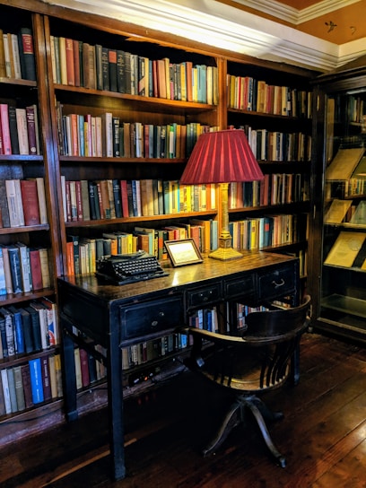 A cozy writing desk with vintage Spanish books and handwritten manuscripts scattered, bathed in warm afternoon light.