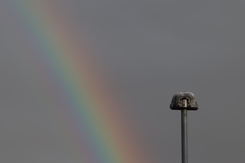 a rainbow is seen in the sky over a pole