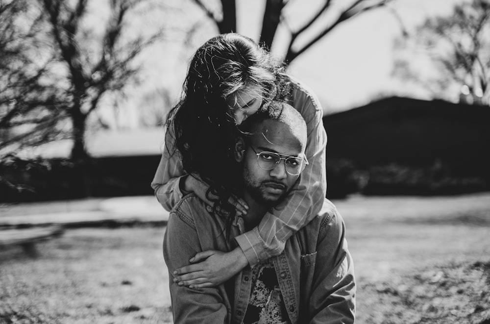 grayscale photography of woman back hugging man