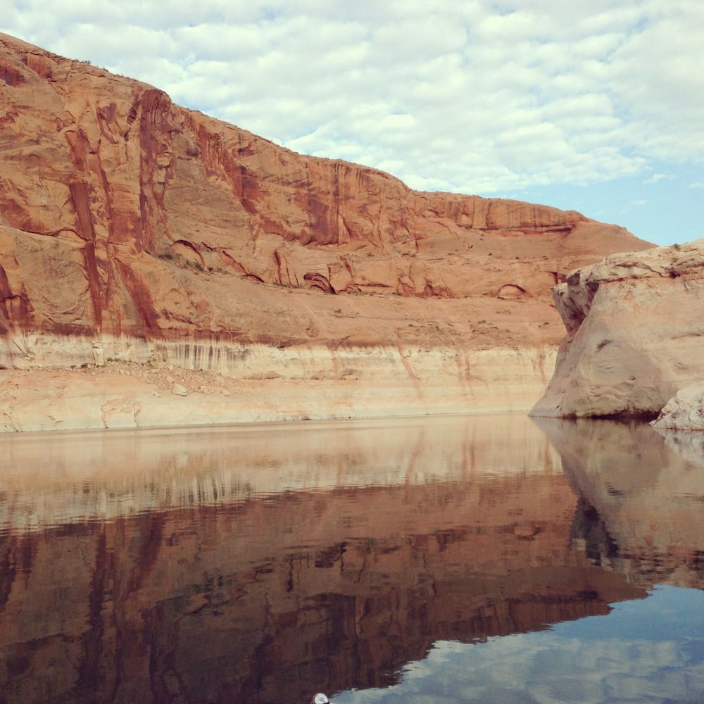 brown rock formation beside body of water