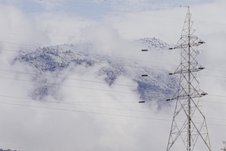 gray transmission tower near mountain during daytime