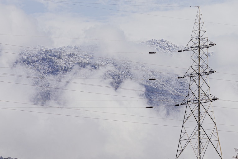 gray transmission tower near mountain during daytime