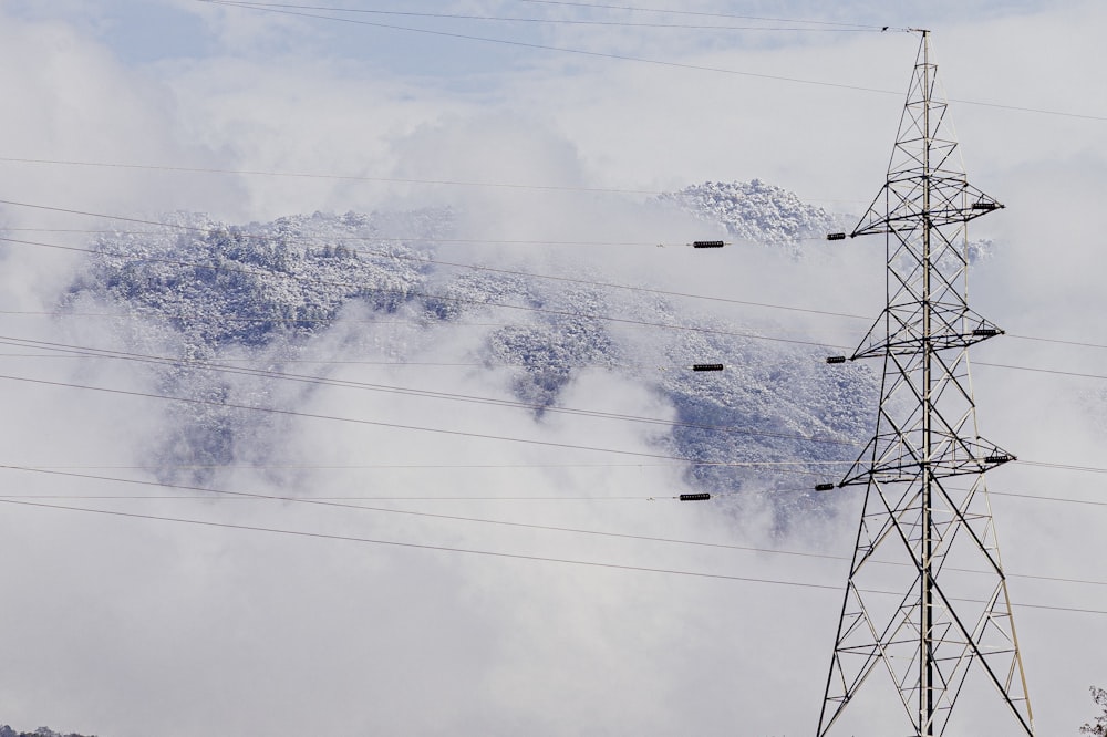 gray transmission tower near mountain during daytime