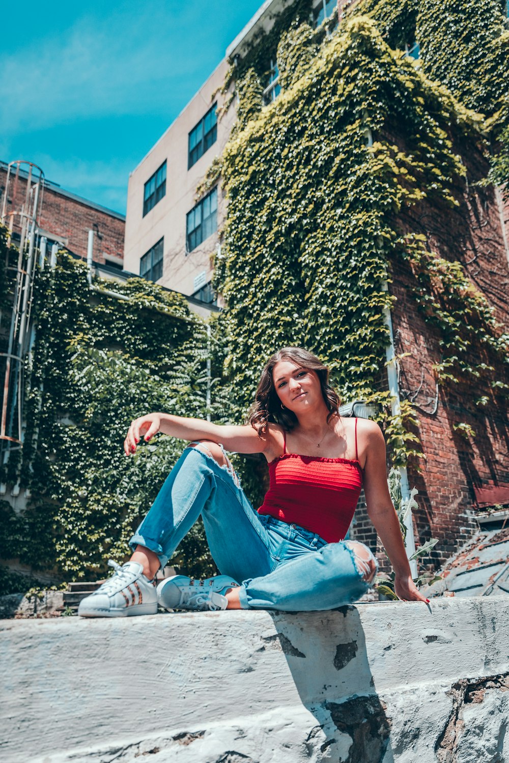 woman wearing red camisole sitting near the house