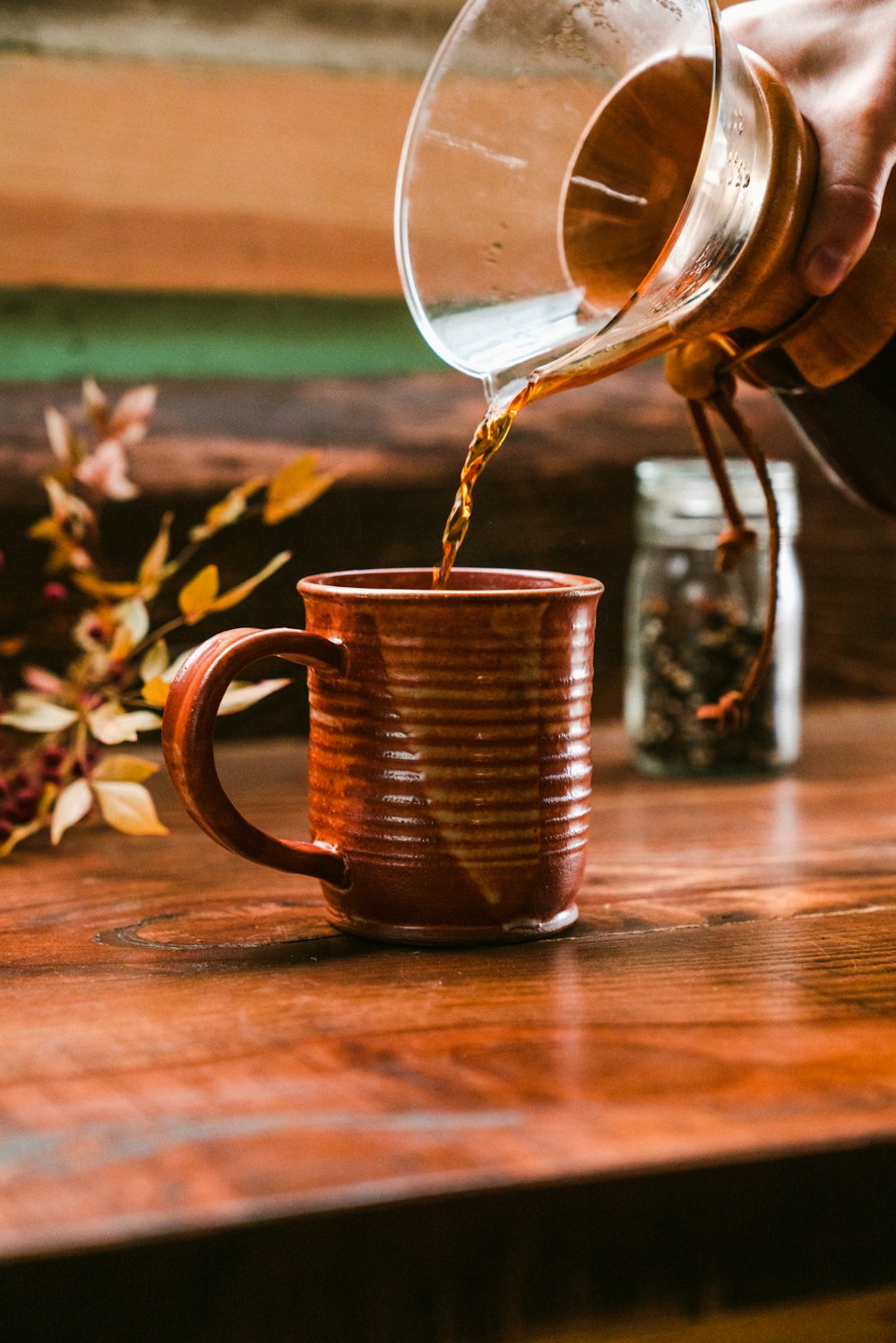 person pouring liquid on brown mug