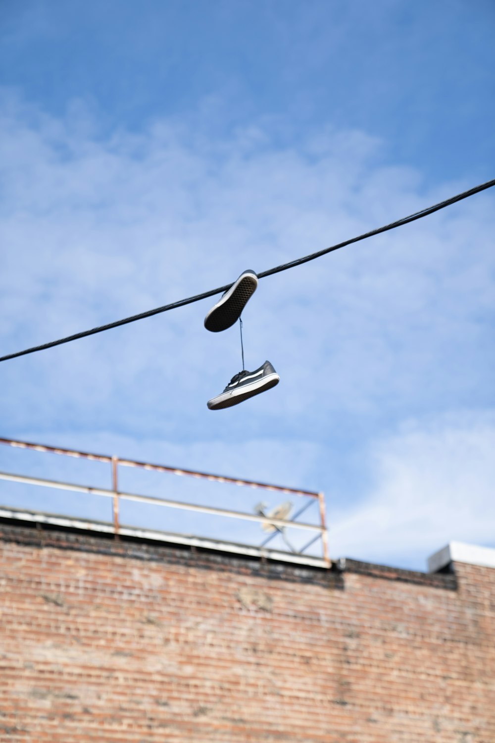 low-angle photography of shoes hanging on cable