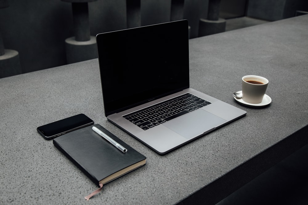 MacBook Pro in der Nähe der Tasse auf dem Schreibtisch