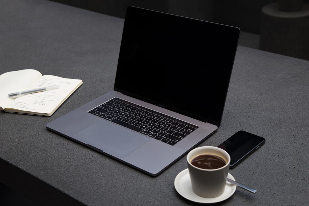 MacBook Pro beside teacup