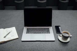 A warm, inviting workspace with a laptop, coffee cup, and a notepad ready for messages.