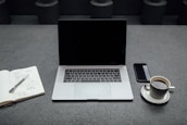 A calm workspace featuring a notebook, coffee cup, and a laptop with funnel analytics on screen.