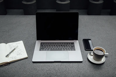 A clean, modern workspace with a laptop, notebook, and coffee cup reflecting organized bookkeeping.
