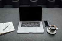 A professional workspace featuring a laptop, notepad, and coffee cup on a desk.