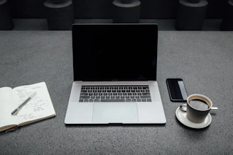 A sleek office workspace with a laptop, coffee cup, and notepad ready for a client meeting.