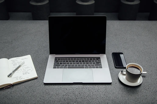 A professional workspace with a laptop, notepad, and a cup of coffee on a clean desk