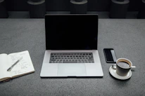 A sleek workspace with a laptop, notebook, and coffee cup, symbolizing creativity and focus.