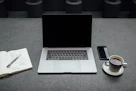 A creative workspace with a laptop, notebook, and coffee cup.