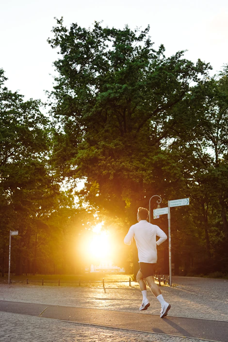 Runner wearing a sleek premium marathon t-shirt with a personalized race log on the back, jogging through a city park at sunrise