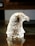 A crystal sculpture of an eagle's head is displayed on a reflective surface. The intricate details of the glass capture the feathers' texture, beautifully refracting light to create a shimmering effect.