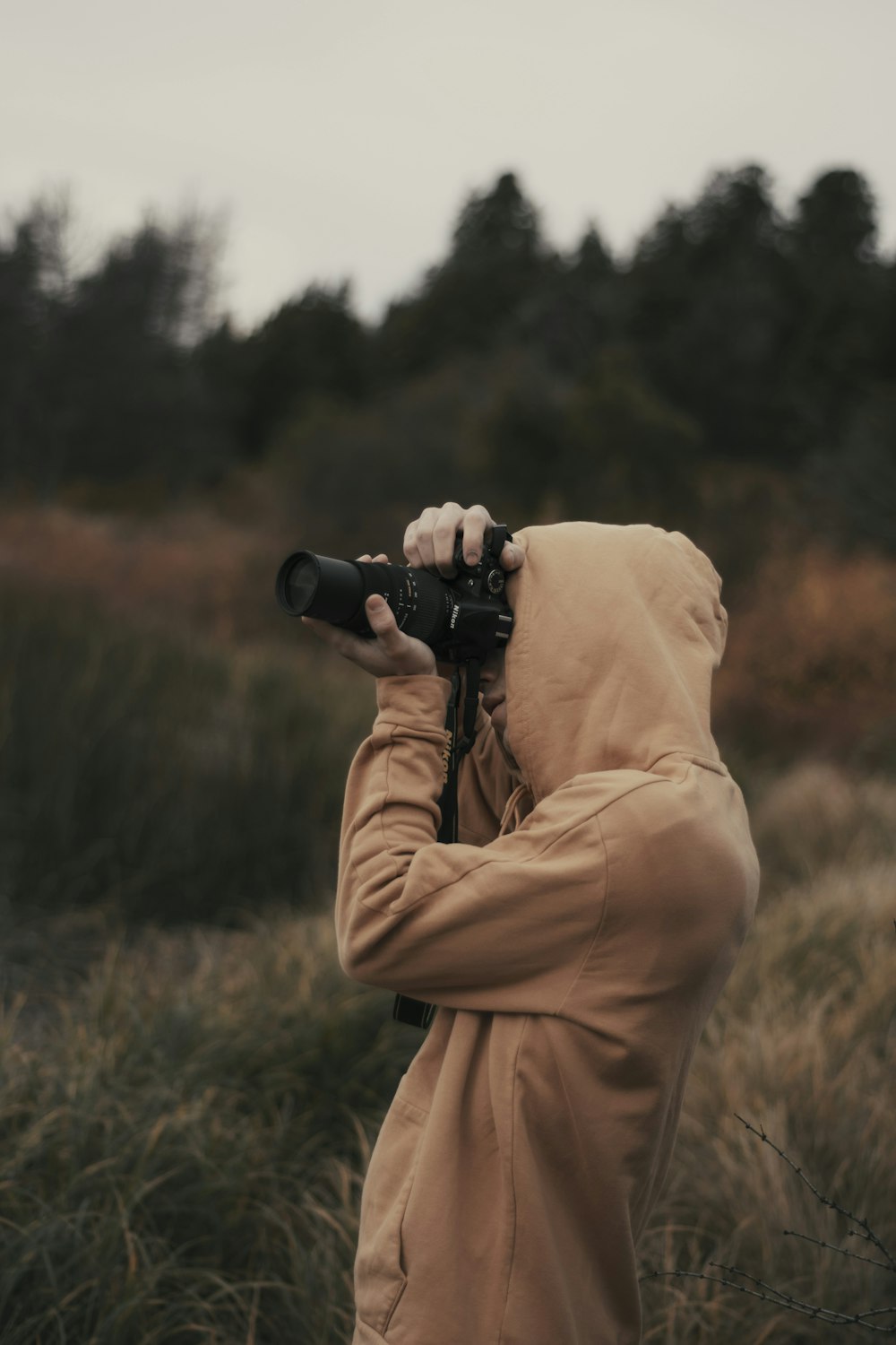 hooded person using a DLSR camera