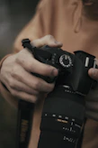 Close-up of hands adjusting camera settings, showcasing the technical side of photography.