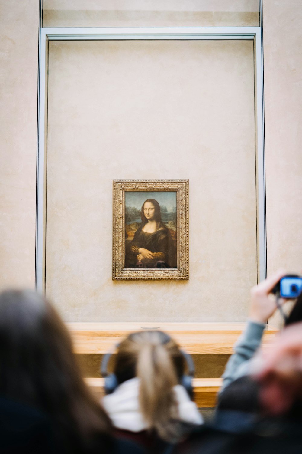 personas frente a la pintura de la Mona Lisa colgada en la pared dentro de la habitación